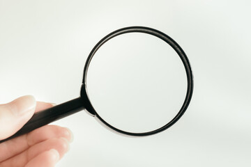 hand holds a magnifier. horizontal photo. business and finance. White background