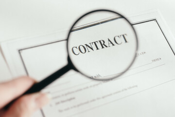hand holds a magnifier. magnifier increases contract. White background.