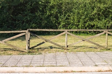 Wooden fence above the sidewalk in front of a public park (Pesaro, Italy, Europe)