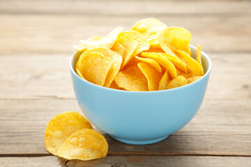 Potato chips on bowl on grey wooden background