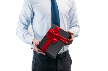 Business man holding a gift with a red ribbon. Guy on a white background in a light shirt with a tie. Black gift box in the hands..