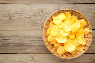Potato chips in basket on grey wooden background.