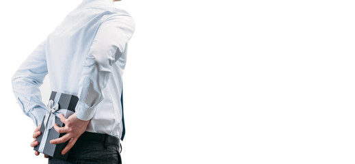 Business man holds a gift behind his back.Guy in a shirt with a tie on a white background. Gift box with a silver ribbon. Narrow panoramic photo..