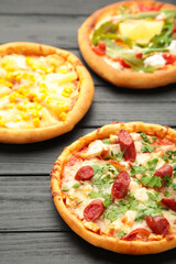 Three different kinds of pizzas on black wooden table. Vertical foto