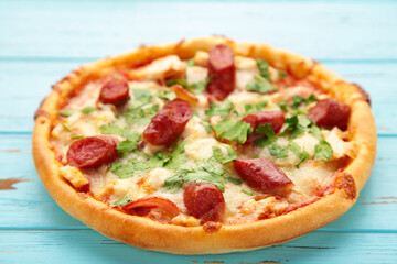 Tasty Italian pizza with sausage on blue wooden table