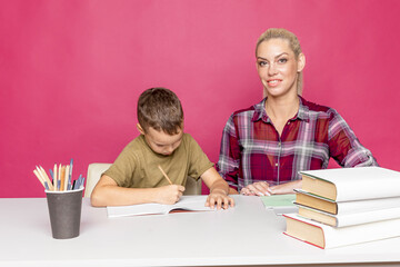 Distance homework with mother at home at quarantine time. Boy with mom sitting at the desk and studying