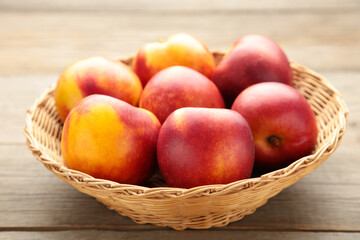 Naklejka na ściany i meble Nectarines in a basket on brown background with copy space