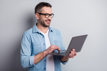 Close-up portrait of his he nice attractive content cheerful cheery focused gray-haired guy company director using laptop browsing isolated over gray light pastel color background