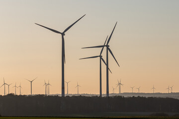 Black Silhouette of windturbines energy generator on amazing sunset at a wind farm in germany