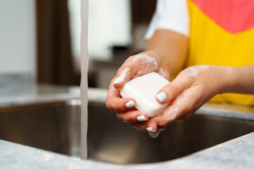 Close up of a woman washing her hands in a kitchen sink