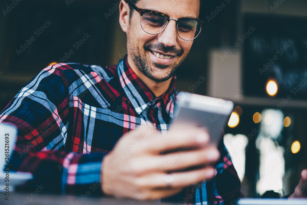 Aufkleber cropped image of cheerful young man in stylish eyewear watching funny video on internet websites usi