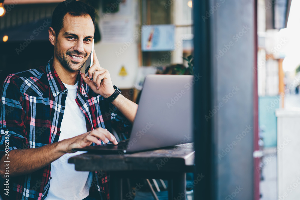 Poster half length portrait of happy young man talking in roaming via mobile tariffs on modern smartphone d