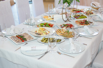 Tasty dishes on a served white banquet table in a luxury restaurant. No people.