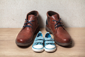 Men's and children's shoes on a wooden floor