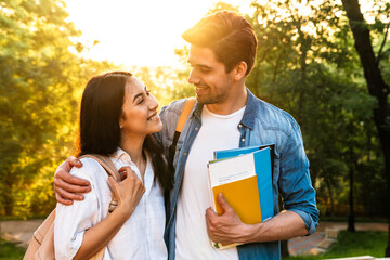 Image of cheerful multicultural student couple hugging and smiling