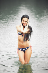 Woman on the beach in a swimsuit with an American flag having fun