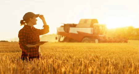 Photo sur Plexiglas Tracteur Agricultrice avec tablette numérique sur fond de moissonneuse. Concept d& 39 agriculture intelligente.