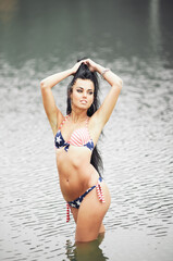 Fototapeta premium Woman on the beach in a bathing suit with an American flag having fun