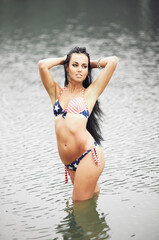 Woman on the beach in a bathing suit with an American flag having fun