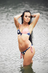 Woman on the beach in a bathing suit with an American flag having fun