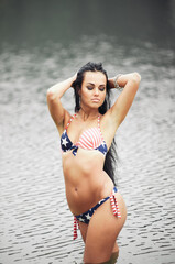 Obraz premium Woman on the beach in a bathing suit with an American flag having fun