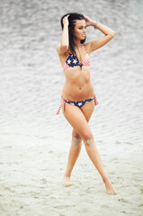Obraz premium Woman on the beach in a bathing suit with an American flag having fun