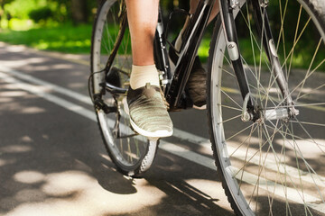 Man foot in sport shoes on the pedal of  mountain bike on outdoor trail in park. Active summer solo outdoor activity. Close up. Man cycling in nature. Training, sport activity and health care.