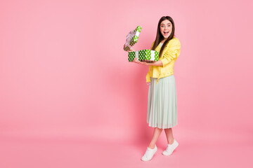 Obraz na płótnie Canvas Full body profile photo of funny lady hold hands large green giftbox opening it overjoyed amazing surprise wear yellow leather jacket long skirt isolated pastel pink color background