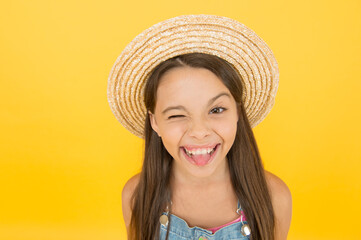 Happy cheerful kid in summer hat yellow background. Funny grimace. Stunning girl in hat. Cheerful face. Emotional child. Summer holidays. Fashionably dressed. Enjoying vacation. Summer fashion