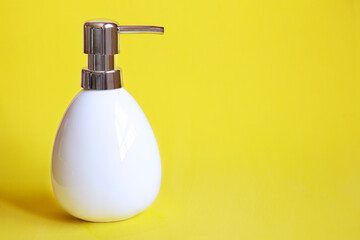 Obraz premium White soap dispenser against yellow background