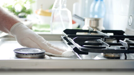 Busy Person in the Kitchen Wearing Gloves Cleans with Solution the Cooker Stove.
