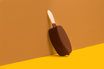 Un helado de chocolate de palo batuta sobre un fondo marrón y amarillo. Vista de frente. Copy space