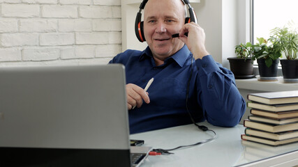 Man Working from Home and Talking in a Video Call Using Laptop Webcam and Headphones, Social...