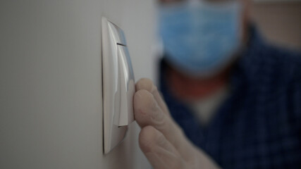 Man Wearing Medical Mask and Protection Gloves Enter in the Office Room Turning On the Light from the Switch on the Wall