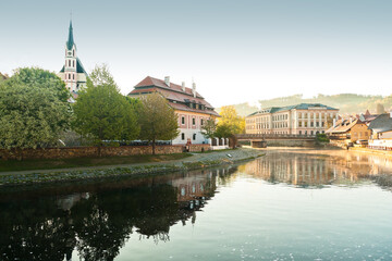 Cesky Krumlov and it St. Vitus church at an early morning golden hour from the riverbank of Vltava river during lockdown
