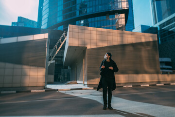 A man in a medical mask on an industrial background of skyscrapers