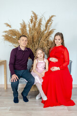 Happy family expecting the second child sitting in sofa in studio