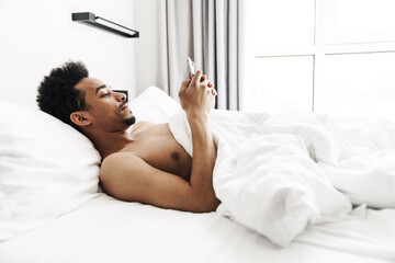 Photo of half-naked african american man mustache using mobile phone