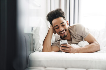 Fototapeta premium Photo of happy african american man using mobile phone and smiling