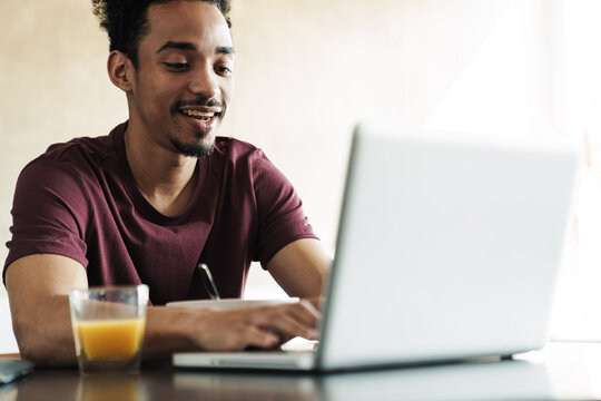 Photo of african american man working with laptop while having breakfast