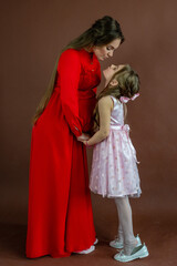 Portrait of beautiful pregnant woman and her cute daughter in studio