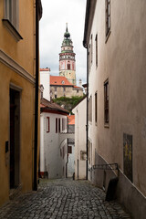 Narrow street and a view of Cesky Krumlov castle tower during a cloudy coronavirus lockdown day without people