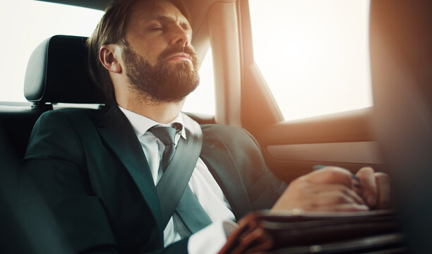 Bearded Businessman With Closed Eyes And Head Leaned Back Sitting On Backseat Of Car While Traveling