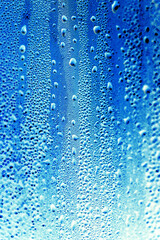 Drops of water on blue glass as an abstract background