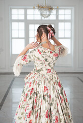 Beautiful woman in long medieval dress in the hall. Back pose