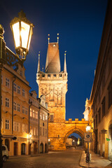 View of illuminated Lesser town tower of Charles bridge in Prague during twilight