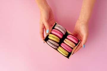 Woman's hands holding box with colorful macaroon cookies