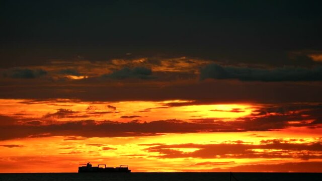 cargo ship moving on sea and sunset red orange colud on sky time lapse