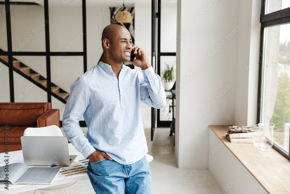 Wall mural Photo of african american man talking on mobile phone while working