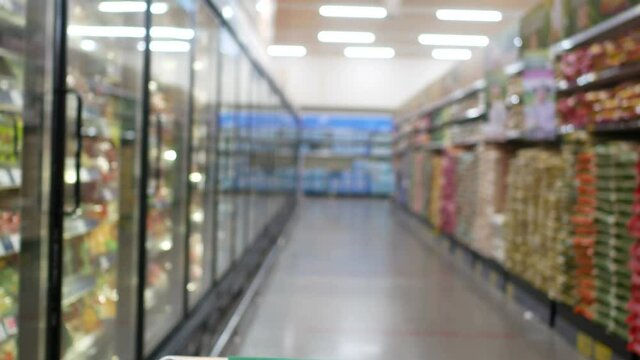 blur defocus of footage walking with cart in supermarket to buy food, drinks , household goods